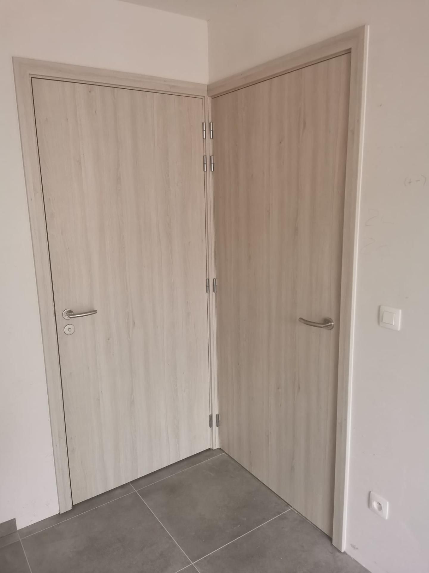 2 houten binnendeuren in een hoek van een kamer - Gebroeders Verduyckt Bocholt